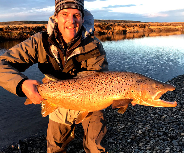 An angler holds a sea-run brown trout in Tierra del Fuego